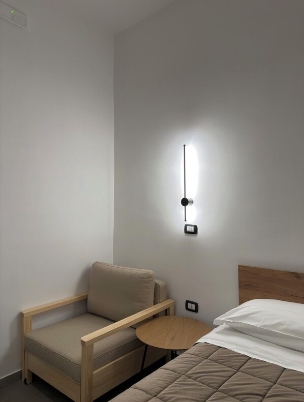 A small, modern room with a bed, a chair, and a small table. - Welcome to i Colori di Napoli (Naples)