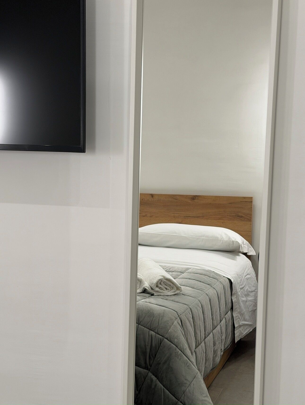 A bedroom with a bed, a wooden headboard, and a white wall.