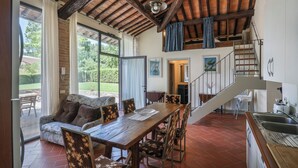 A spacious living area with a wooden dining table, comfortable seating, and a view of the outdoors.
