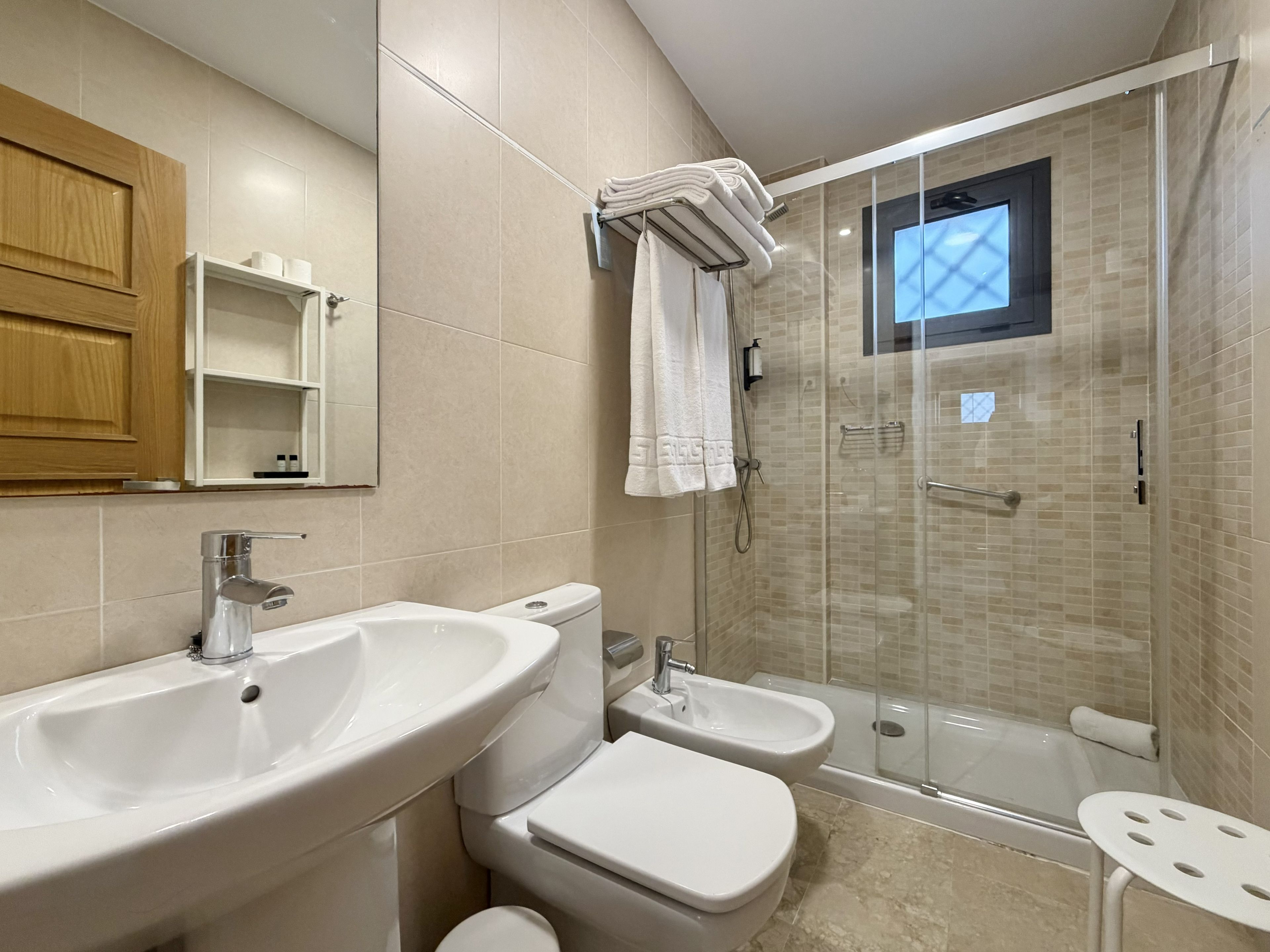 Ein modernes Badezimmer mit einem großen Waschbecken, Toilette, Bidet und einer Duschkabine.