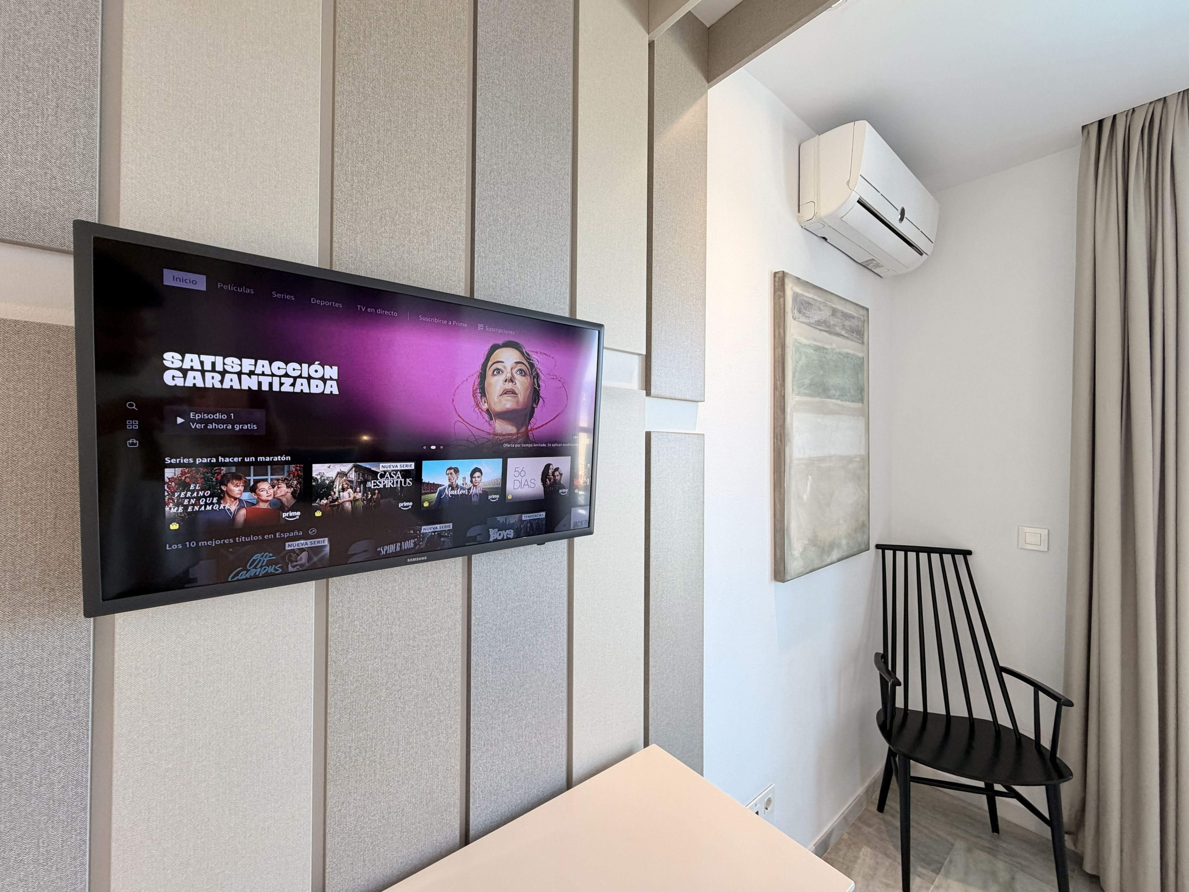 A flat-screen TV mounted on a wall displaying a streaming service interface with various content options.