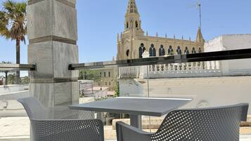 Un área de estar al aire libre con dos sillas y una mesa, con vista a un edificio histórico con una torre alta.