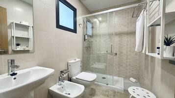 Un baño moderno con bañera, ducha y bidé. Hay un lavabo y un espejo encima.