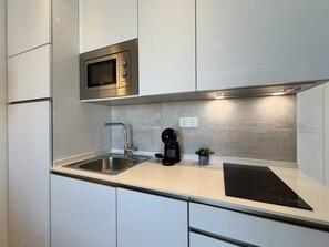Una cocina moderna con electrodomésticos de acero inoxidable, microondas integrado y cafetera.