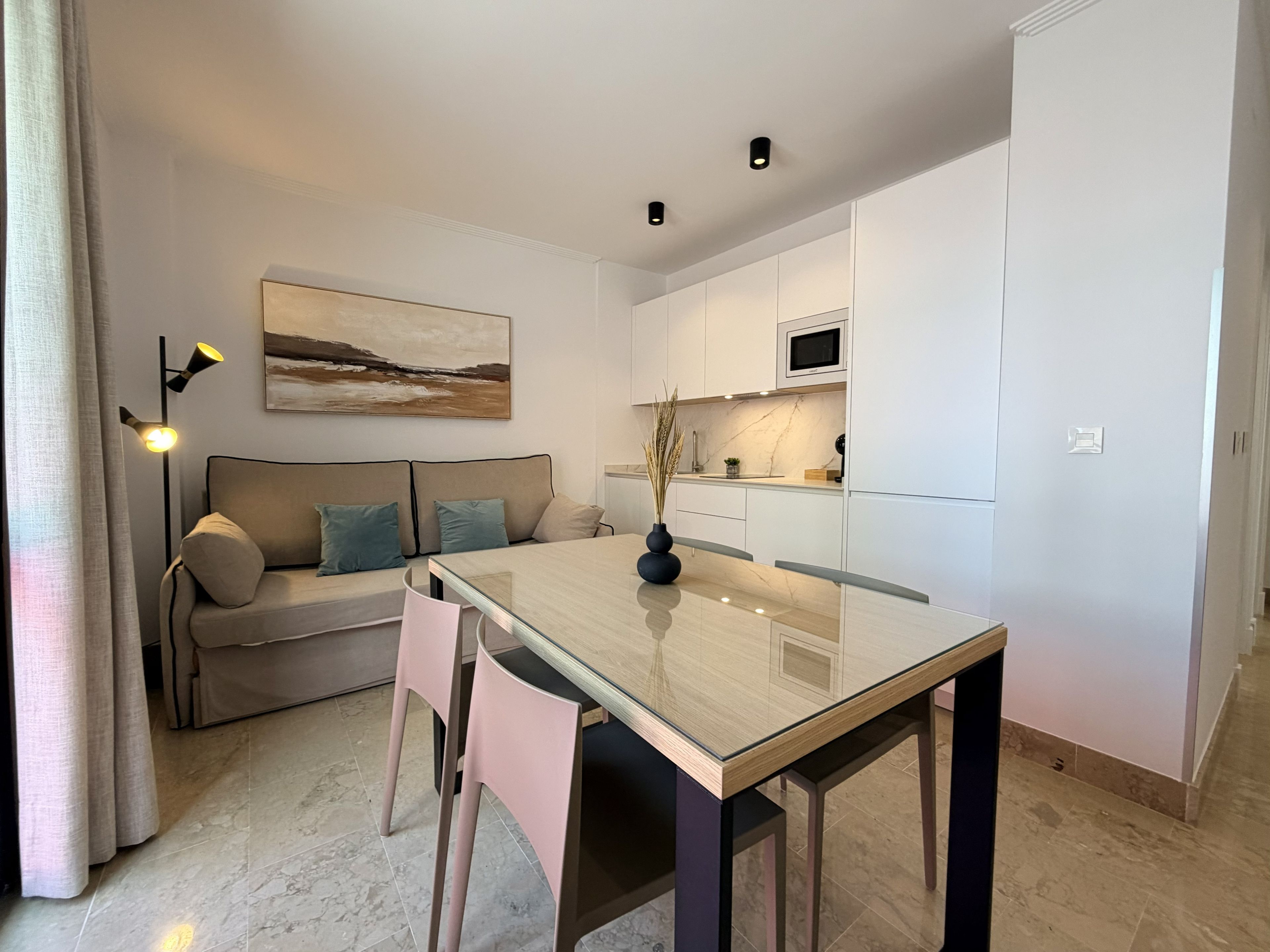 Una cocina moderna con armarios blancos, una mesa de comedor y un sofá con cojines.