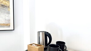 A tray with a stainless steel kettle, two black mugs, and a wooden box on a wooden table against a white wall. - Hotel Apartamentos Marina Luz (Chipiona)