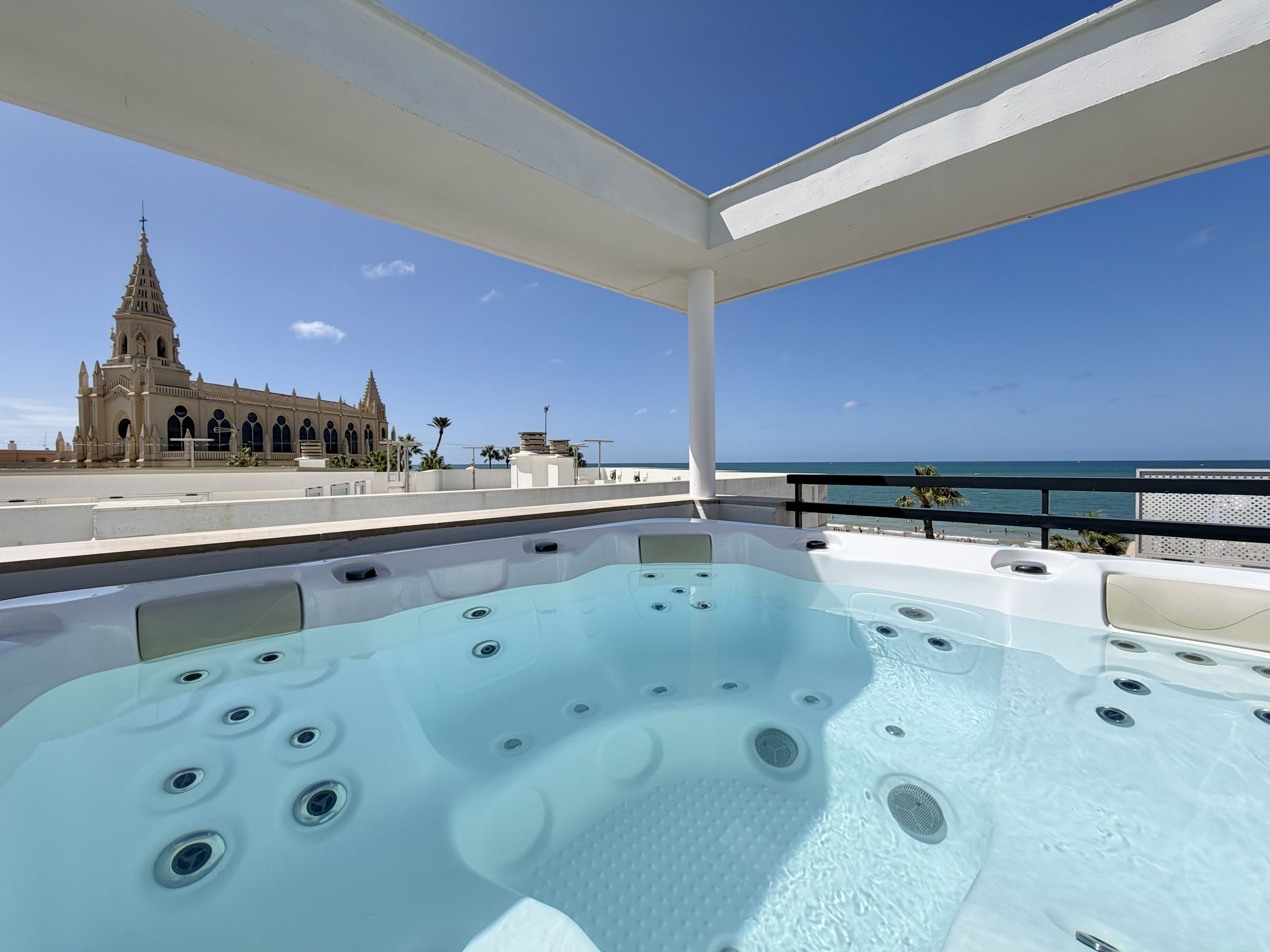 A hot tub with a view of a church and the sea.