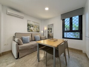 Una sala de estar moderna con sofá, mesa de comedor y ventana con vistas.