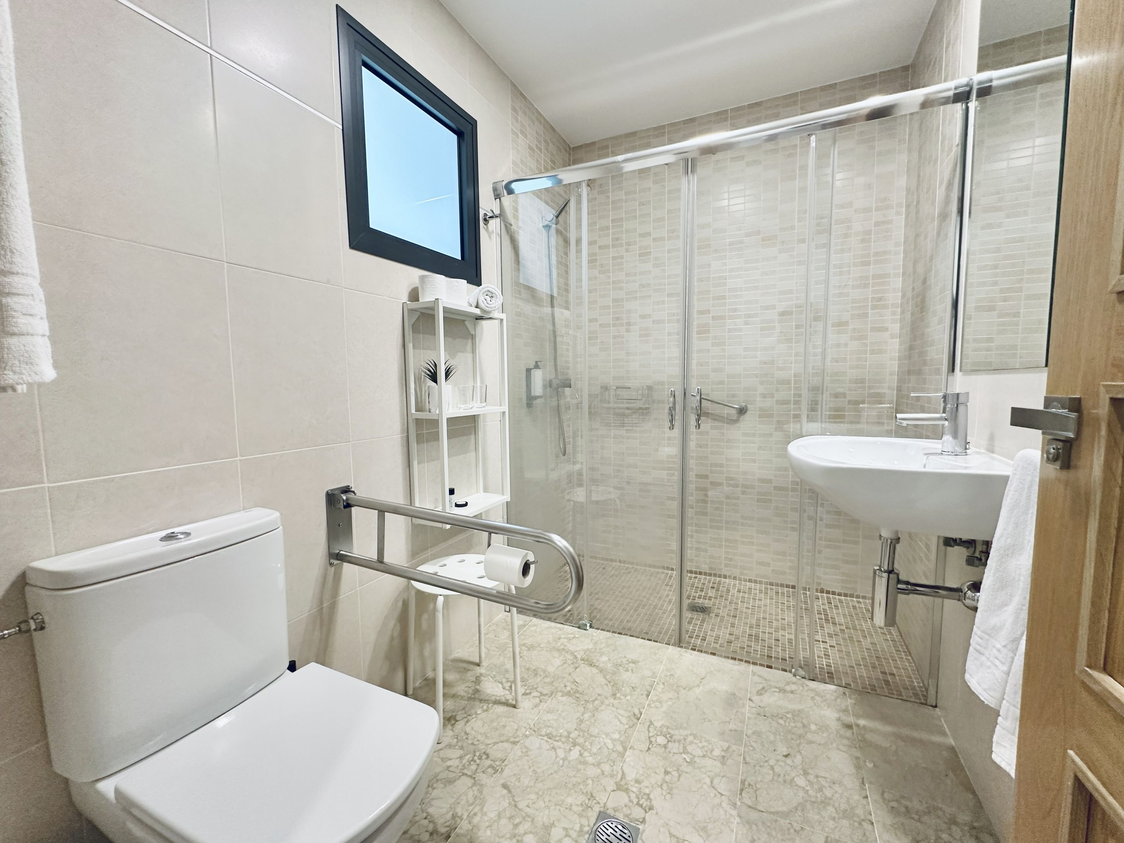 A bathroom with a toilet, a shower enclosure, a sink, and a towel rack.