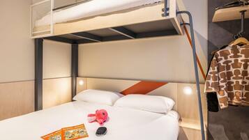 Ein Stockbett mit unterem Bett, ein Nachttisch mit Lampe, ein Kuscheltier und ein Buch auf dem Bett.