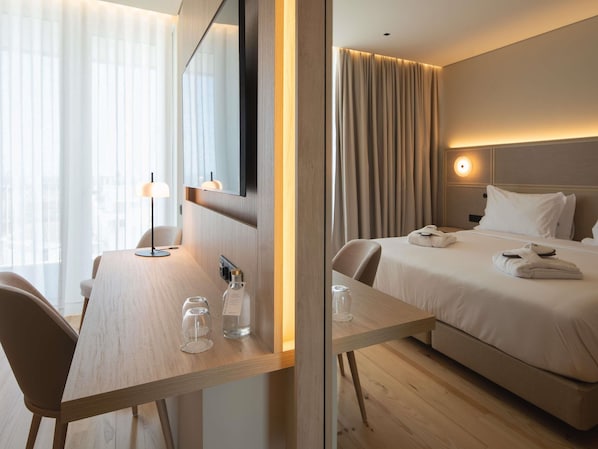 A hotel room with a bed, bedside table, and a desk with a chair.