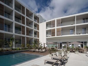 A modern hotel with multiple balconies, a pool area, and outdoor seating. - Mercure Ponta Delgada Azores (Ponta Delgada)