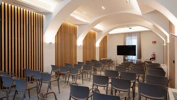 Ein Konferenzraum mit Reihen von Stühlen, einem großen Flachbildfernseher und Holzwandverkleidung.