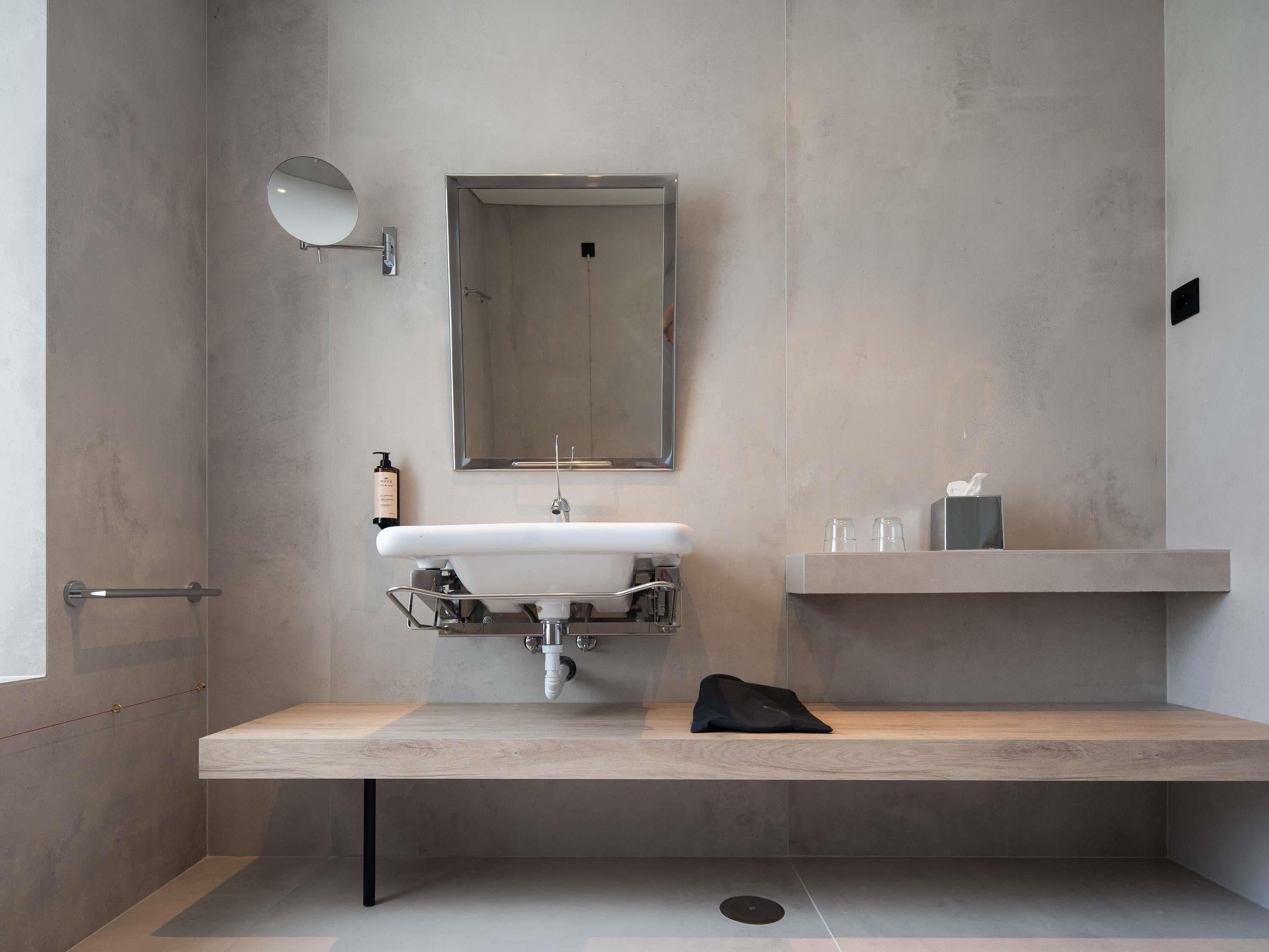 A modern bathroom with a built-in sink, a mirror, and a towel rack.
