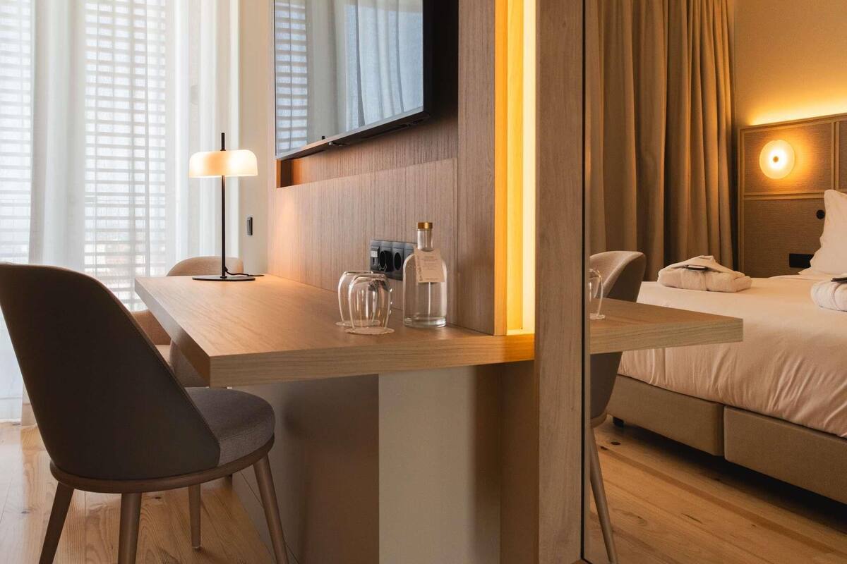 Ein Hotelzimmer mit Schreibtisch, Stuhl, Bett und einem großen Spiegel.