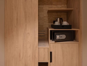 A wooden cabinet with a microwave, a coffee maker, and a black box on top.