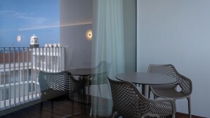 A balcony with wicker chairs and a table, overlooking a building with a clock tower. - Mercure Ponta Delgada Azores (Ponta Delgada)