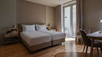 Habitación de hotel con cama doble, un escritorio con silla, mesita de noche y puerta corrediza de vidrio que da a un espacio al aire libre.
