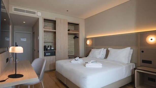 Una camera d'albergo con un letto, comodini, una scrivania e una sedia.