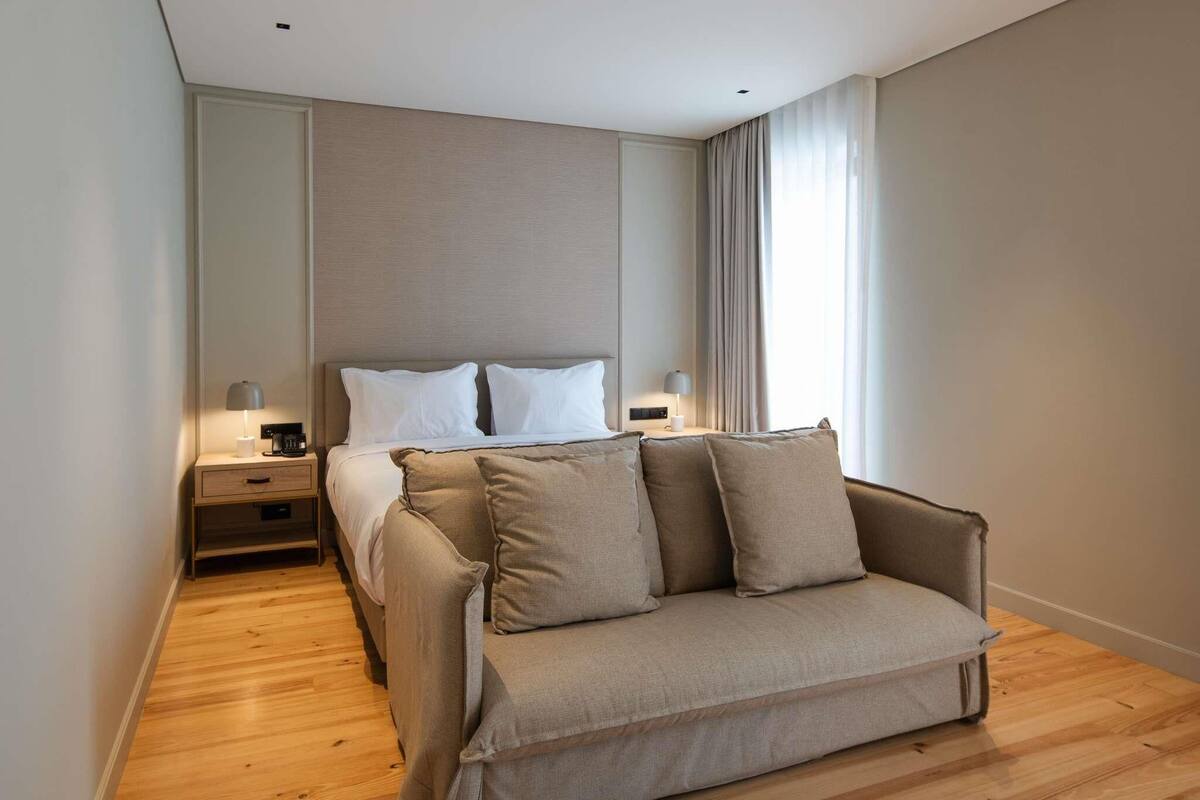 Ein modernes Hotelzimmer mit Bett, Sofa, Nachttisch und Lampe.