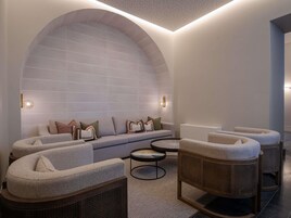 A modern lounge area with a curved sofa, round coffee table, and wicker chairs.