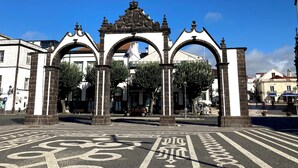 A historic archway with intricate designs and a central emblem, leading to a plaza with a bike lane. - Mercure Ponta Delgada Azores (Ponta Delgada)