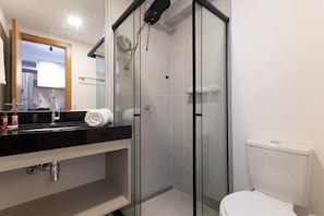 A bathroom with a glass-enclosed shower, a white toilet, and a black countertop with a sink. - Porto Privilege Housi by Carpediem (Salvador)