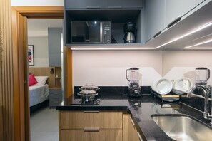 A compact kitchen with a microwave, coffee maker, blender, and sink.