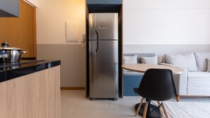 Una cocina moderna con un refrigerador empotrado, una encimera de madera y una mesa de comedor redonda con una silla negra.