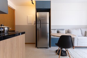 Eine moderne Küche mit einem eingebauten Kühlschrank, einer Holz Arbeitsplatte und einem runden Esstisch mit einem schwarzen Stuhl.