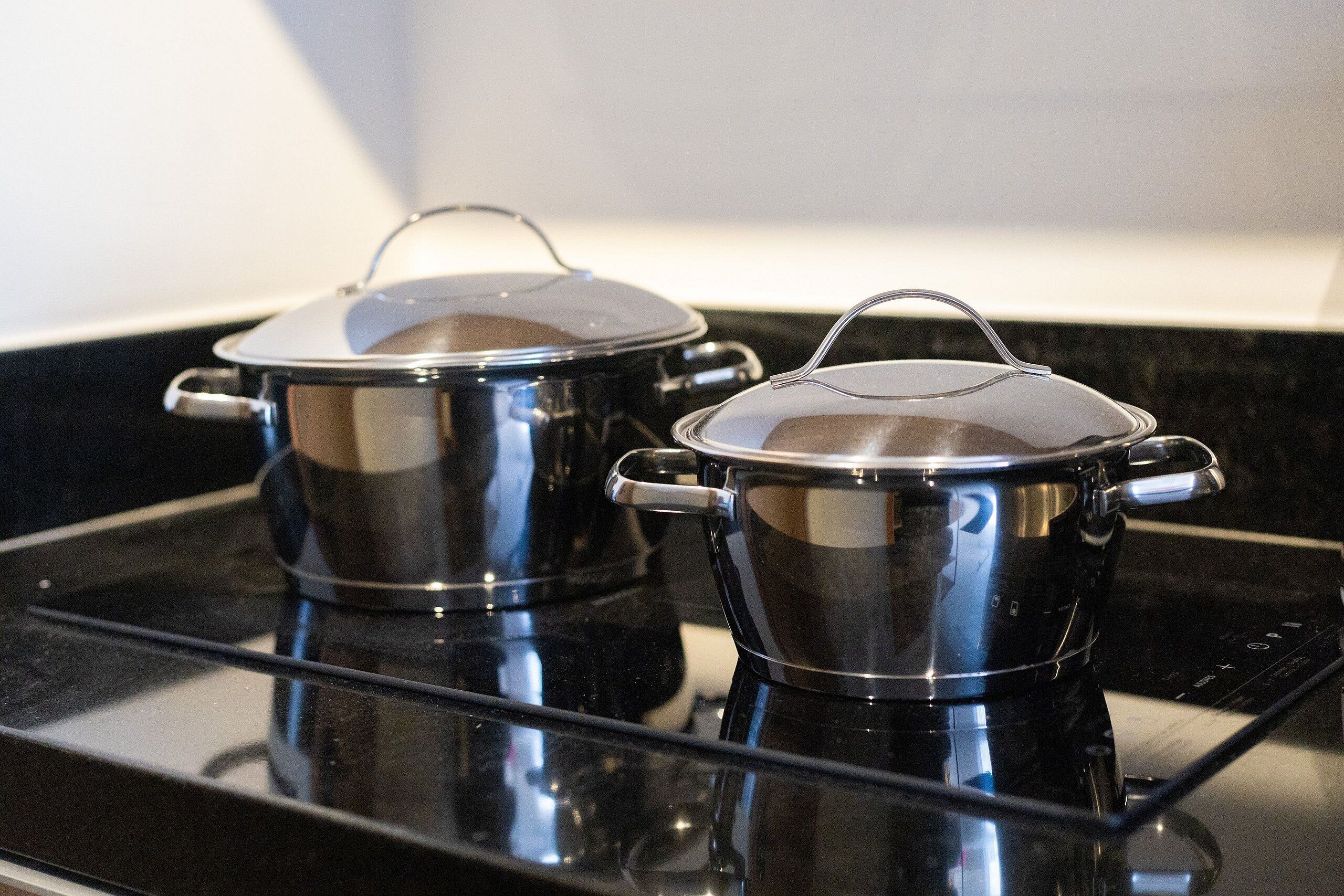 Two stainless steel pots on a black stovetop.