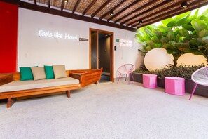 A reception area with a wooden bench, a pink chair, and a large plant. - Porto Privilege Housi by Carpediem (Salvador)