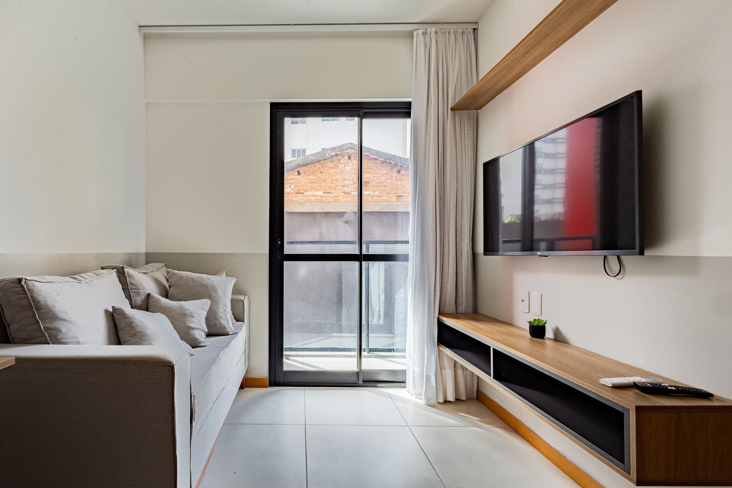 Una sala de estar moderna con un sofá, un televisor de pantalla plana, un ventanal corredero y una mesa consola de madera.
