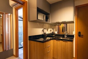 Una cocina compacta con encimera negra, armarios de madera, horno empotrado y cafetera.