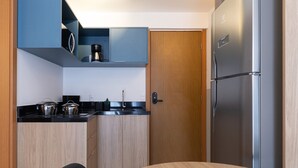 Una cocina funcional con refrigerador, armarios y una mesa de comedor.