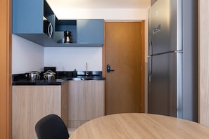 Eine kleine Küche mit Kühlschrank, Schränken und einem Esstisch.