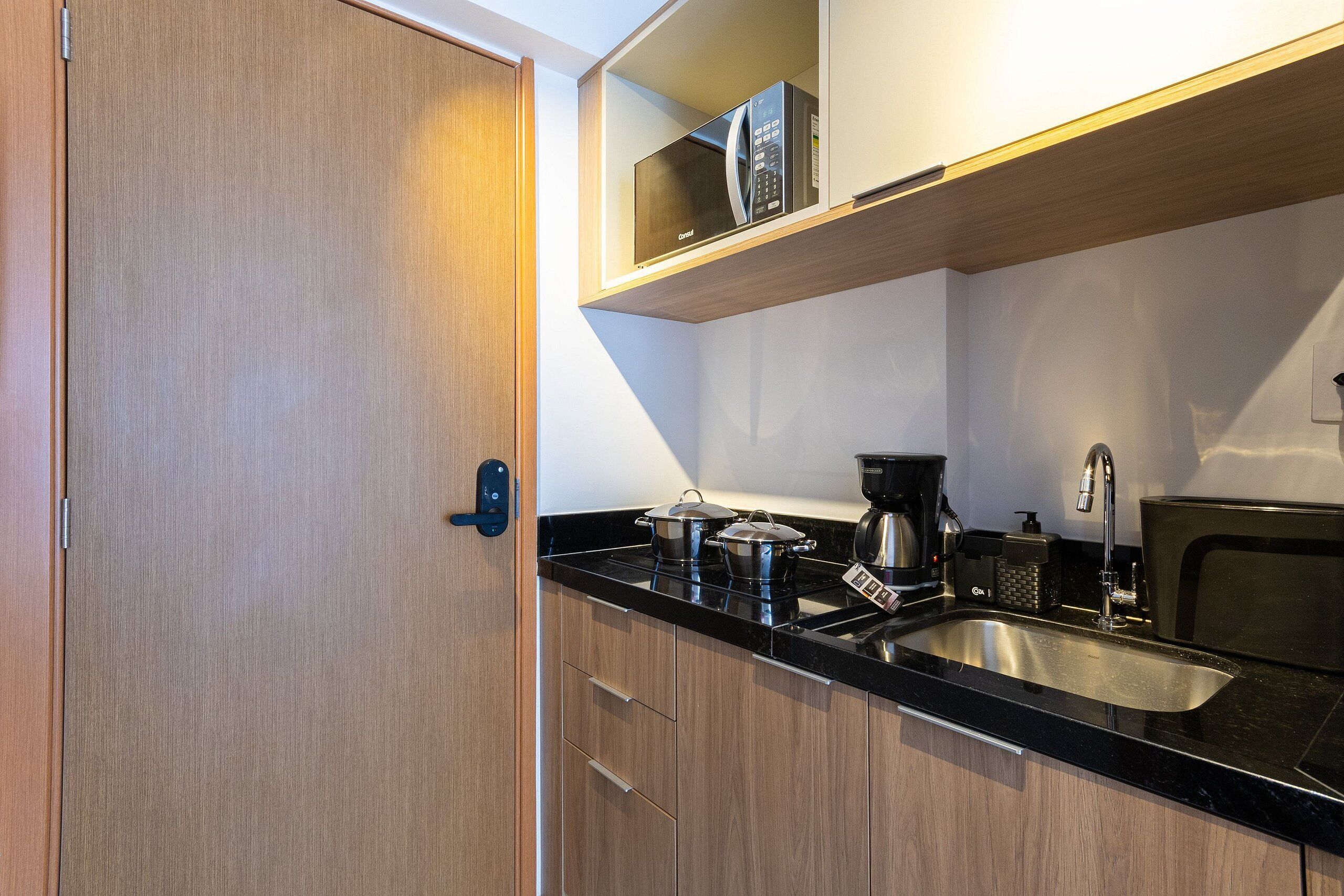 A compact kitchen with a microwave, stove, sink, and wooden cabinets.