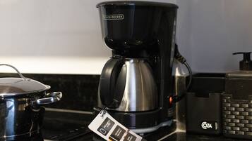 Uma cozinha com cafeteira, chaleira e dispensador Cota.