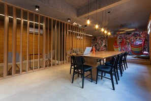 A modern meeting room with a long wooden table, black chairs, and a laptop.