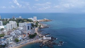 Luftaufnahme einer Küstenstadt mit Hochhäusern, Strand und felsiger Küstenlinie.