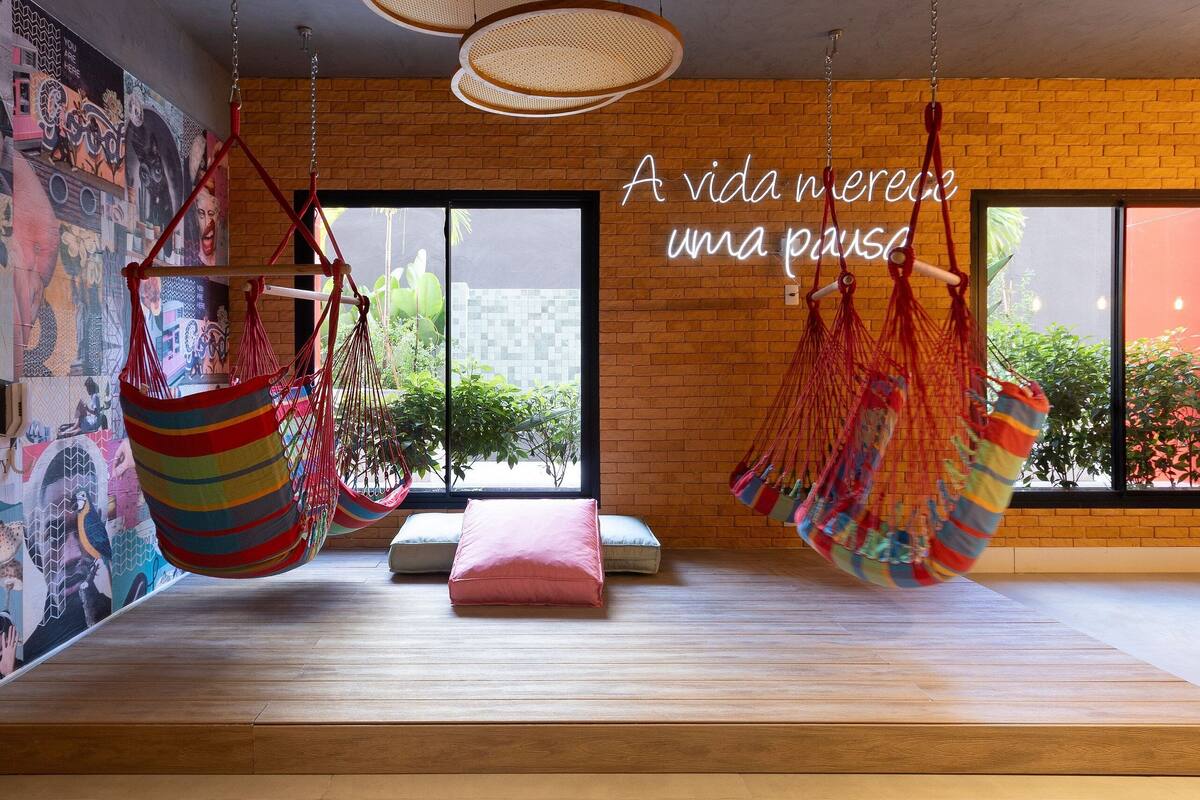 A room with hanging hammocks, a brick wall, and a mural.