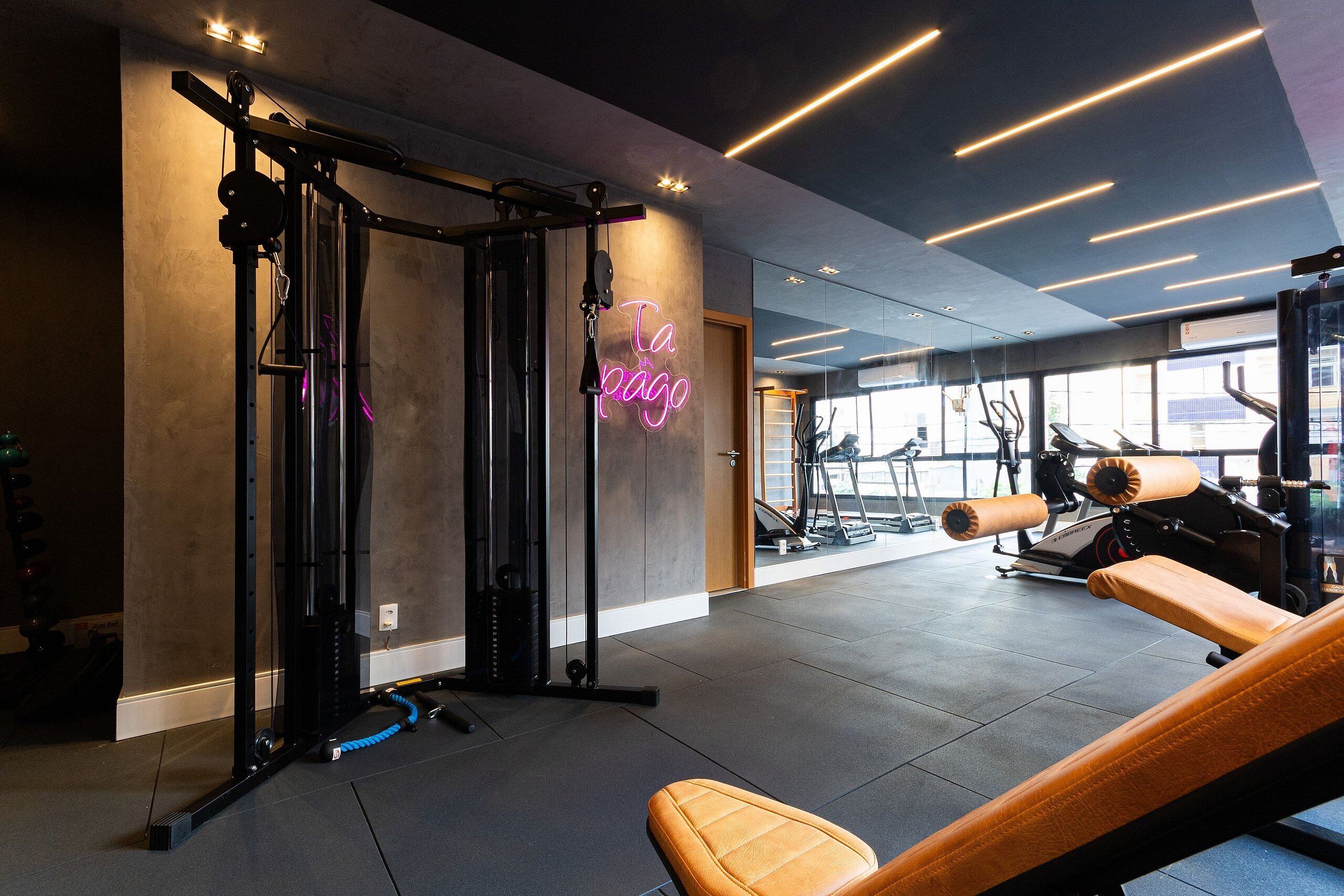 A gym with exercise equipment, a neon sign, and large windows.