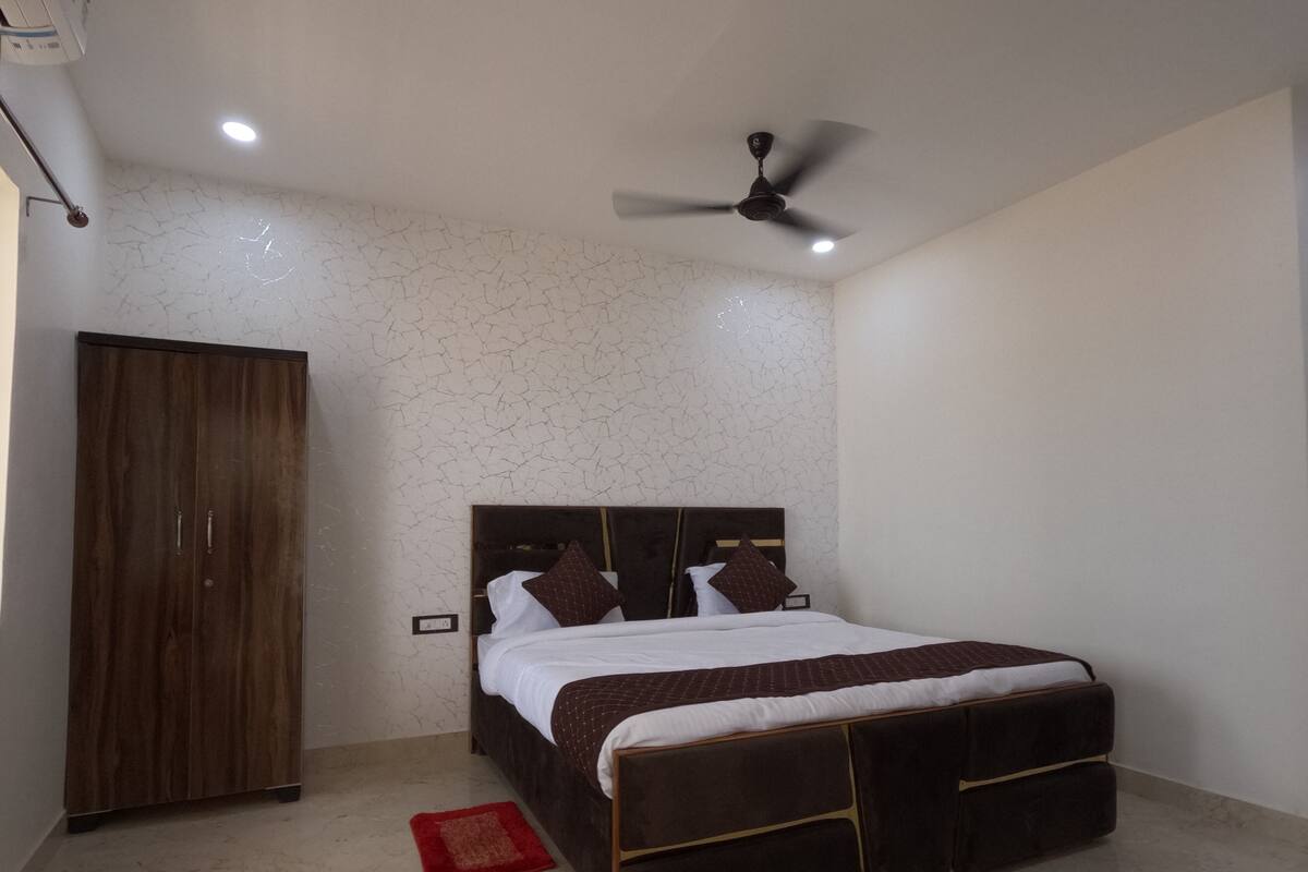 A bedroom with a bed, a wardrobe, a ceiling fan, and a red rug.