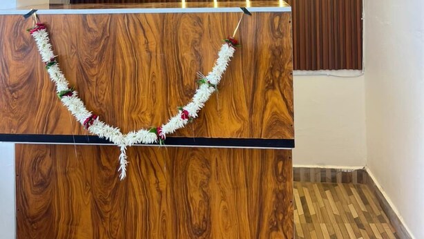Un espace d’accueil avec un comptoir de réception en bois, des lambris verticaux sur le mur et une guirlande de fleurs blanches.