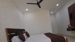 Une chambre à coucher avec un lit, un ventilateur de plafond, des spots encastrés, un tapis rouge et une tête de lit en bois.