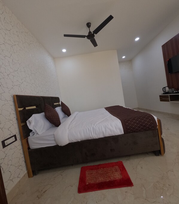 Un dormitorio con cama, ventilador de techo, luces empotradas, alfombra roja y cabecero de madera.