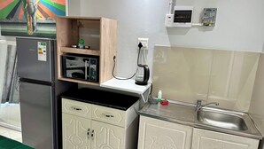 A compact kitchen with a refrigerator, microwave, and a coffee maker. - Mowetu Guest House (Cape Town)