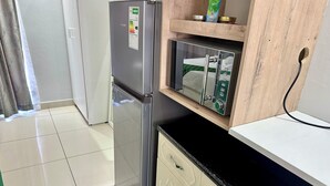 A compact kitchen with a stainless steel refrigerator, a microwave, and a built-in oven. - Mowetu Guest House (Cape Town)