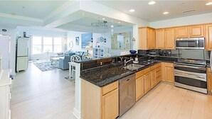 A spacious kitchen with wooden cabinets, stainless steel appliances, and a large island. - 4BR Waterfront Penthouse Pool Views (Virginia Beach)