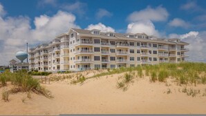 A multi-story hotel with balconies, located on a sandy beach with dunes. - 4BR Waterfront Penthouse Pool Views (Virginia Beach)